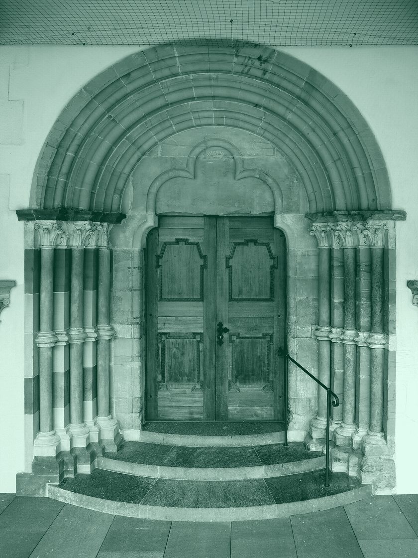 A carved stone portal with a wooden door, in deep green duotone