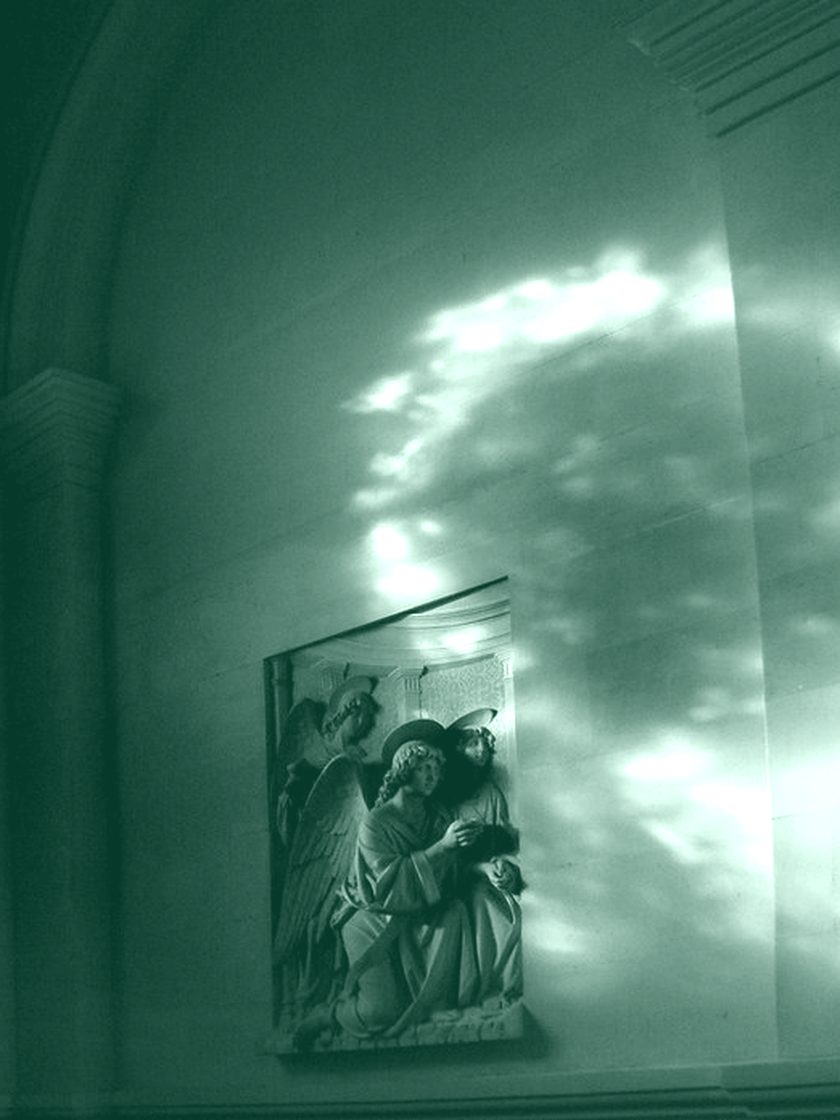 Coloured light falling across a stone church wall, in deep green duotone