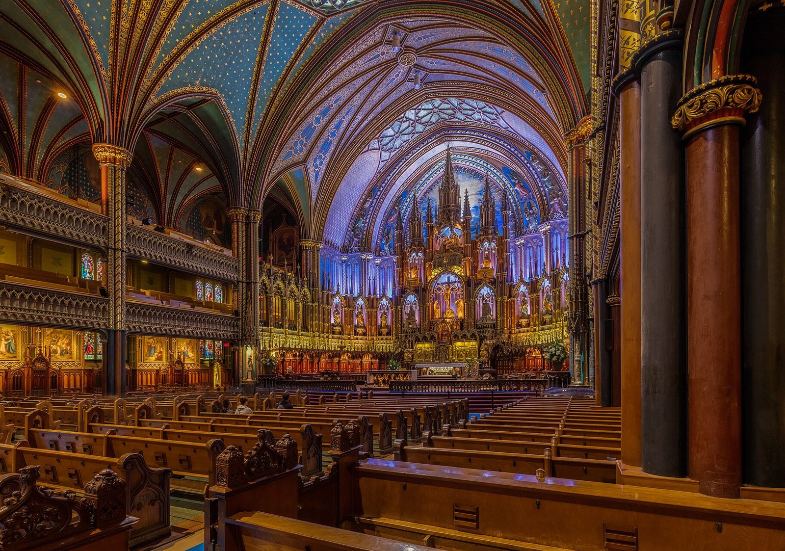 The nave of Notre-Dame Basilica in Montreal, wooden pews under a deep blue and gold vaulted ceiling